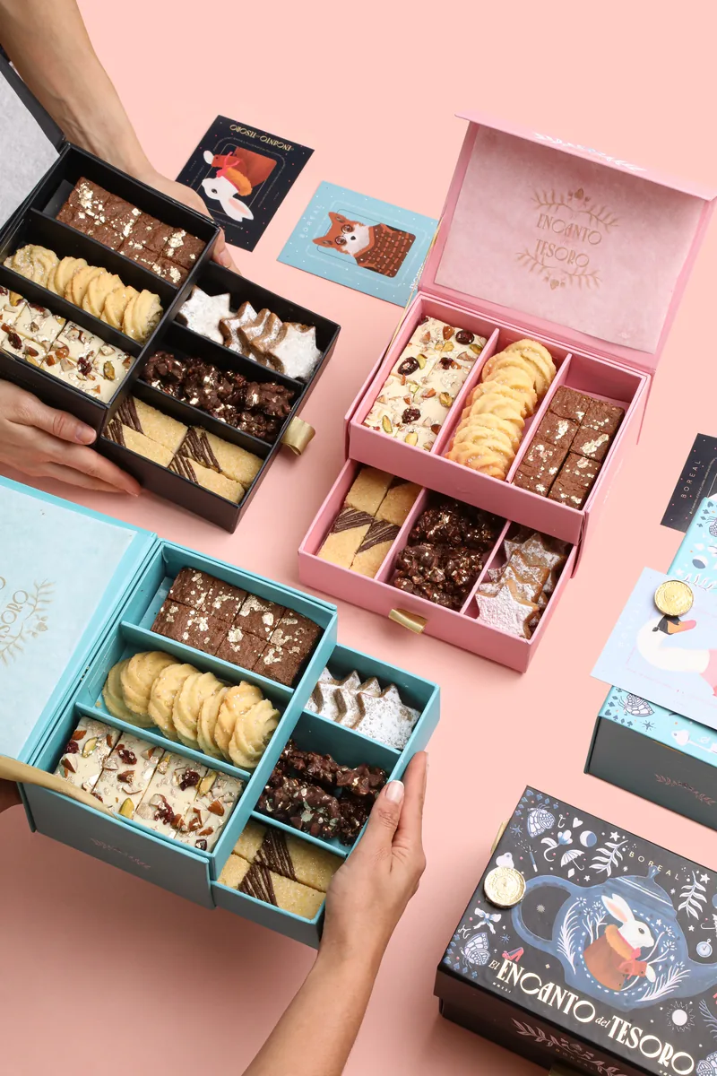 Manos sosteniendo cajas abiertas de galletas y brownies de Boreal